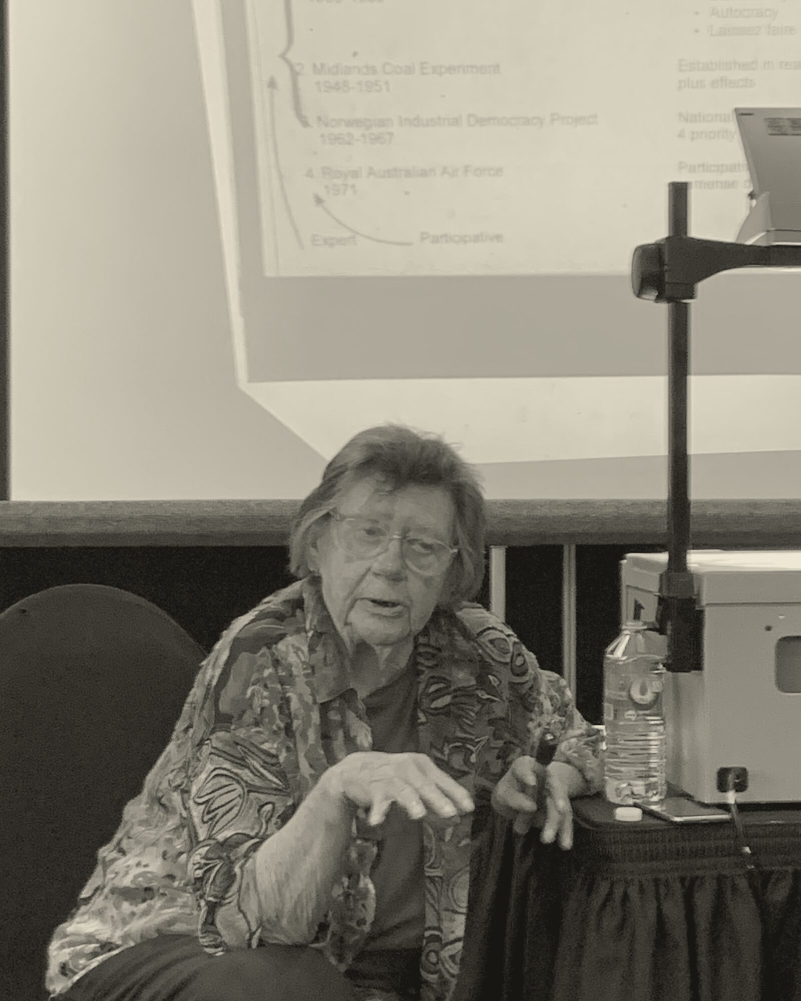 Merrelyn Emery teaching at an OST workshop in front of a slide showing the major landmarks in the history of work redesign.